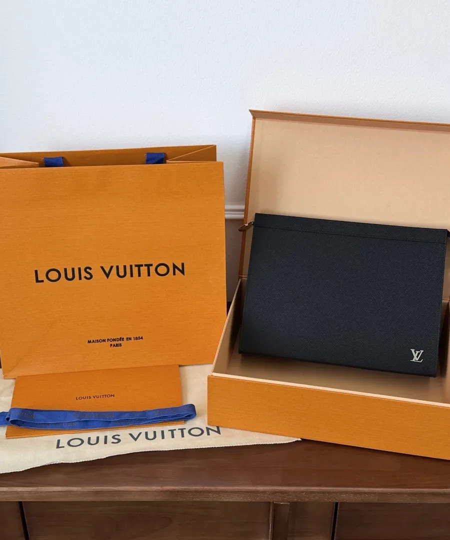 Черный клатч Louis Vuitton Pochette Voyage рядом с фирменной коробкой и пакетом