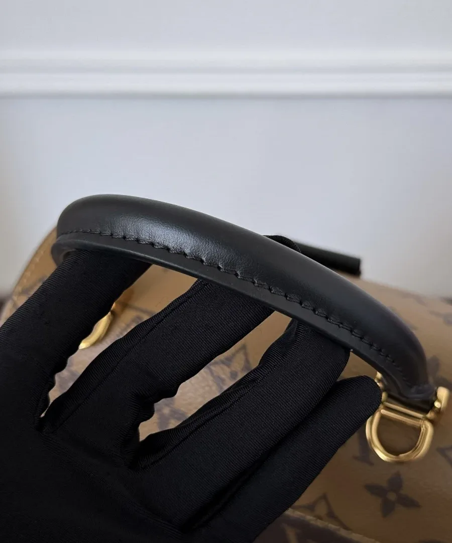 Черная кожаная ручка сумки Louis Vuitton Tilsitt в руке в перчатке