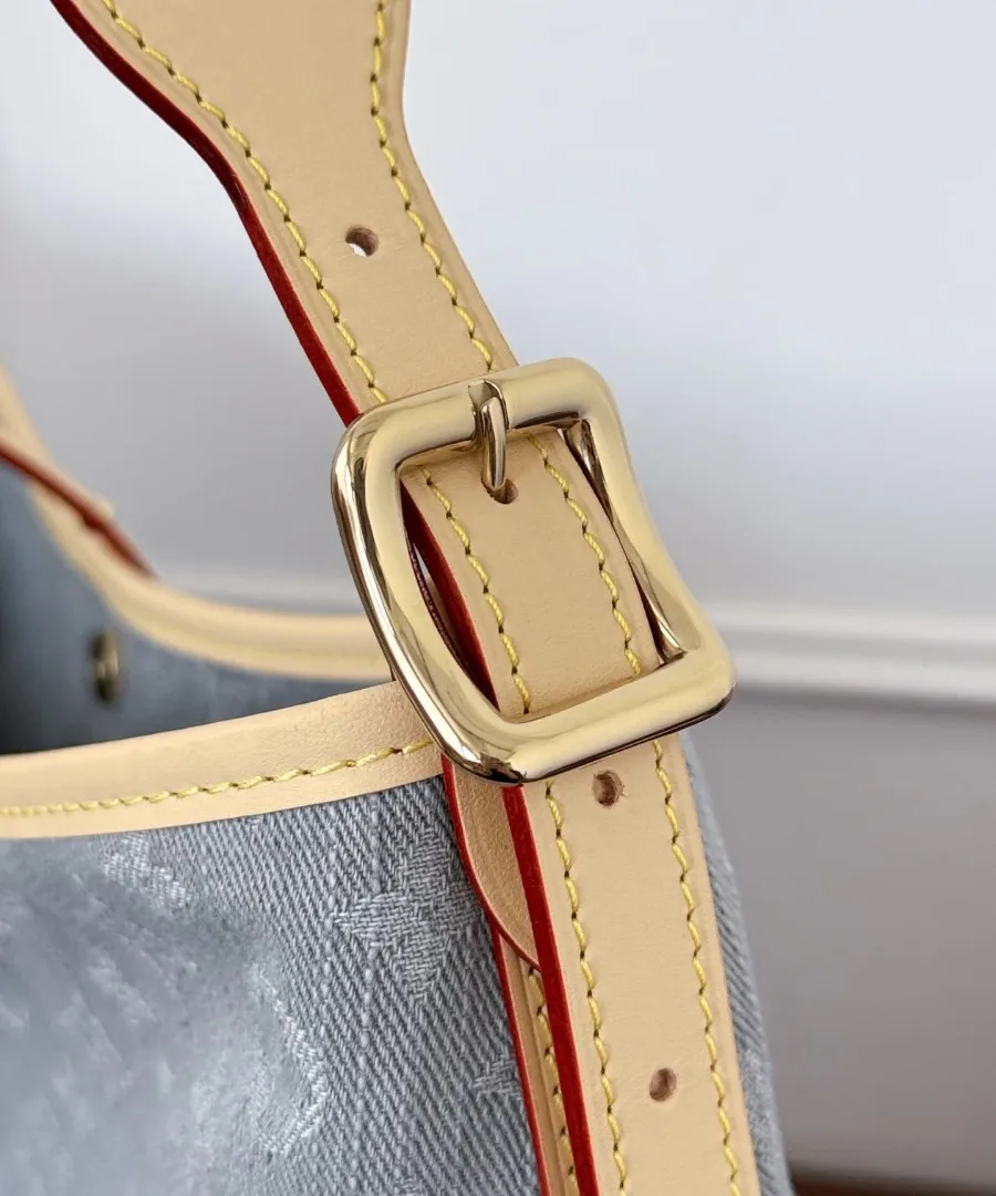 Крупный план золотистой пряжки на кожаном плечевом ремне сумки Louis Vuitton