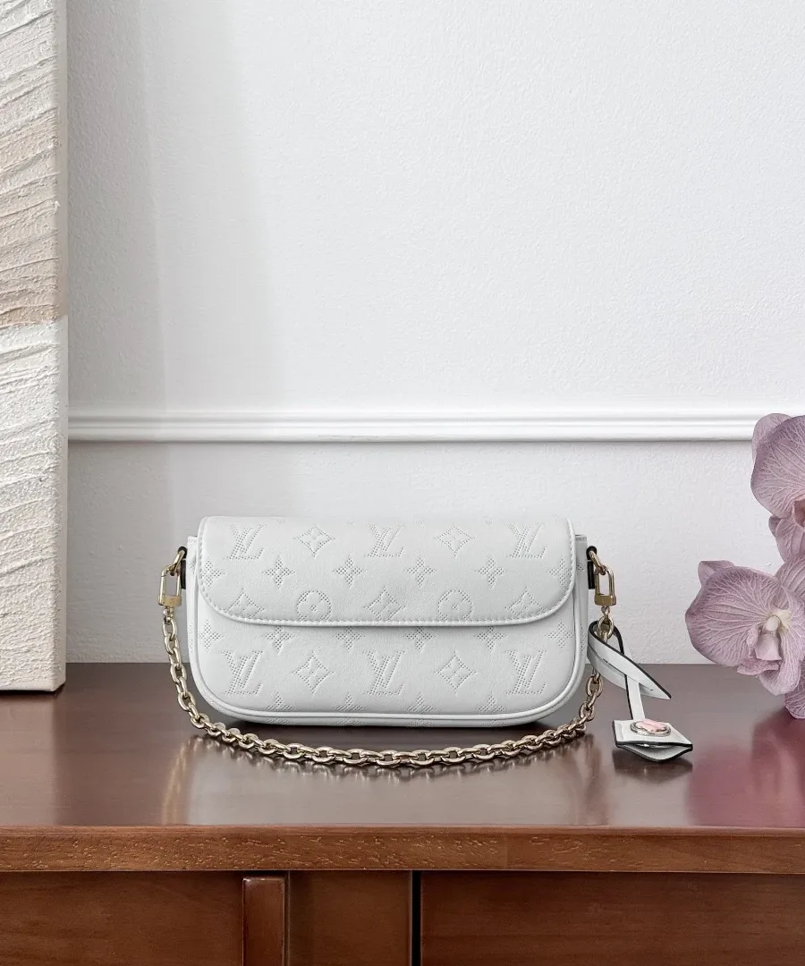 Белая сумка Pochette Ivy с золотистой цепочкой на деревянном столе