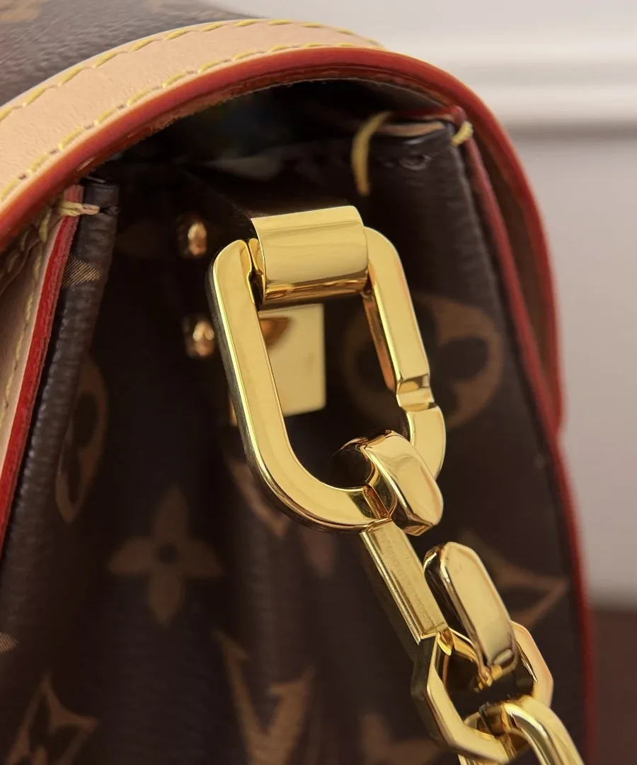 Крупный план золотистого карабина и цепочки сумки Louis Vuitton.