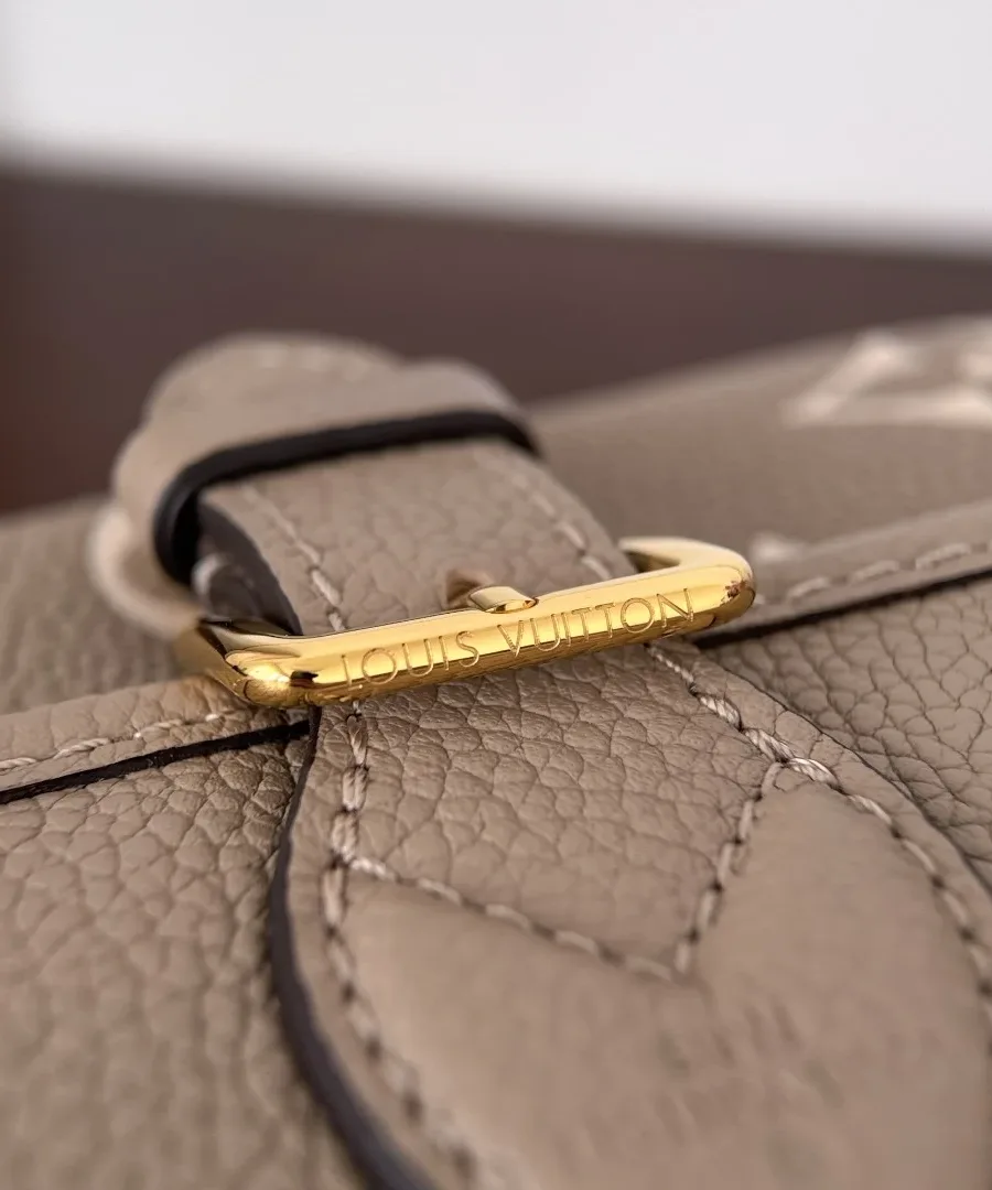 Крупный план золотистой пряжки с гравировкой Louis Vuitton