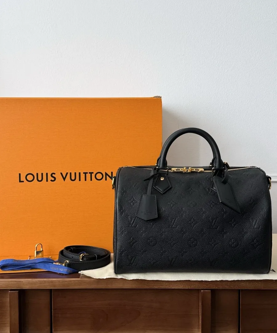 Черная сумка Louis Vuitton Speedy 30 рядом с фирменной оранжевой коробкой и пыльником