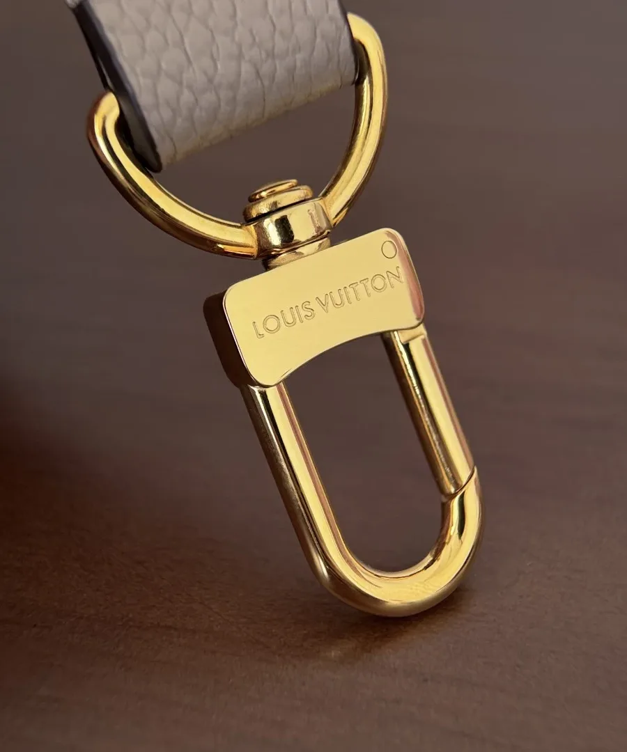 Крупный план золотистого карабина с гравировкой Louis Vuitton