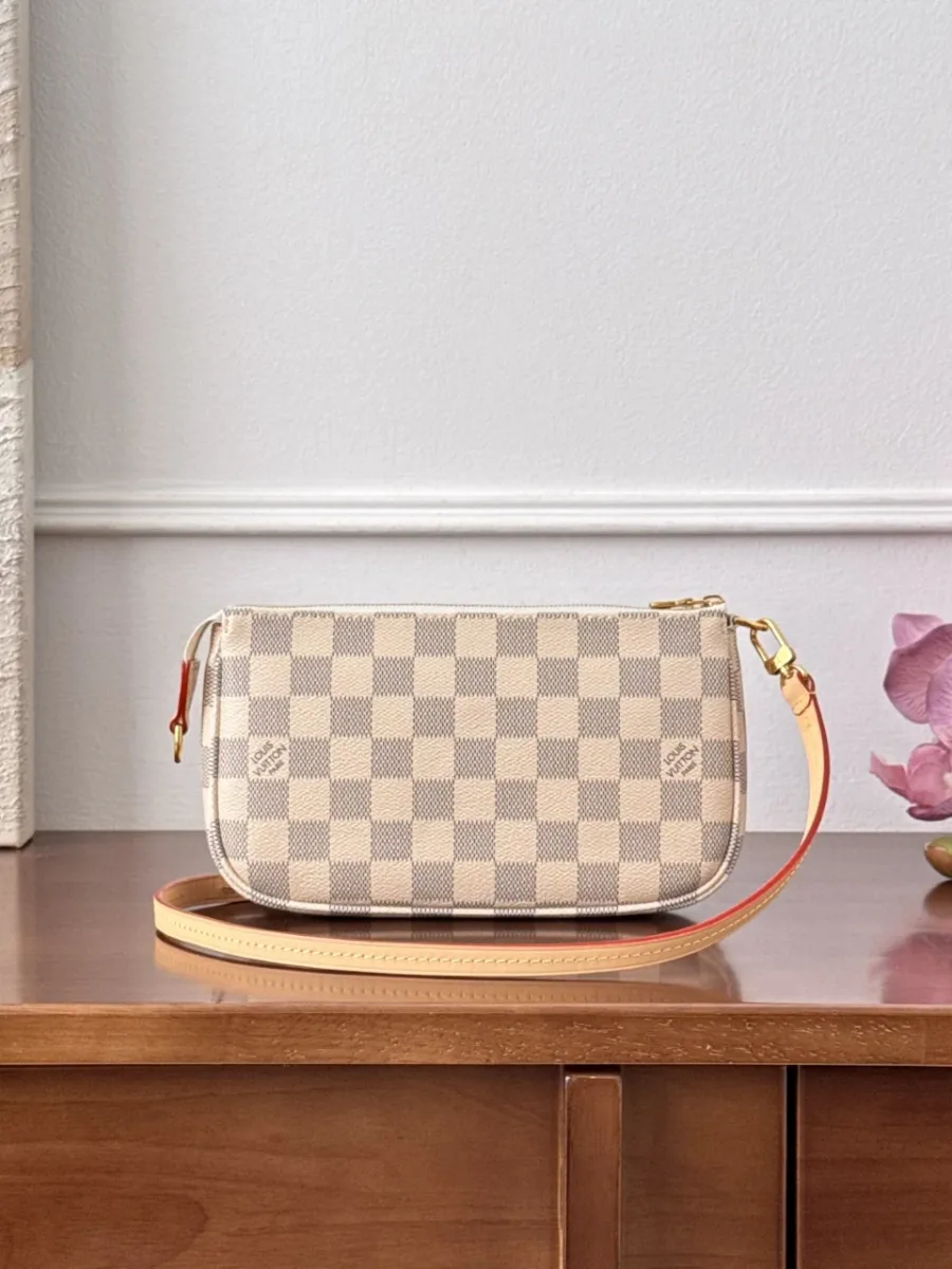 Сумка Louis Vuitton Pochette Accessoires с кожаным ремешком на деревянном столе