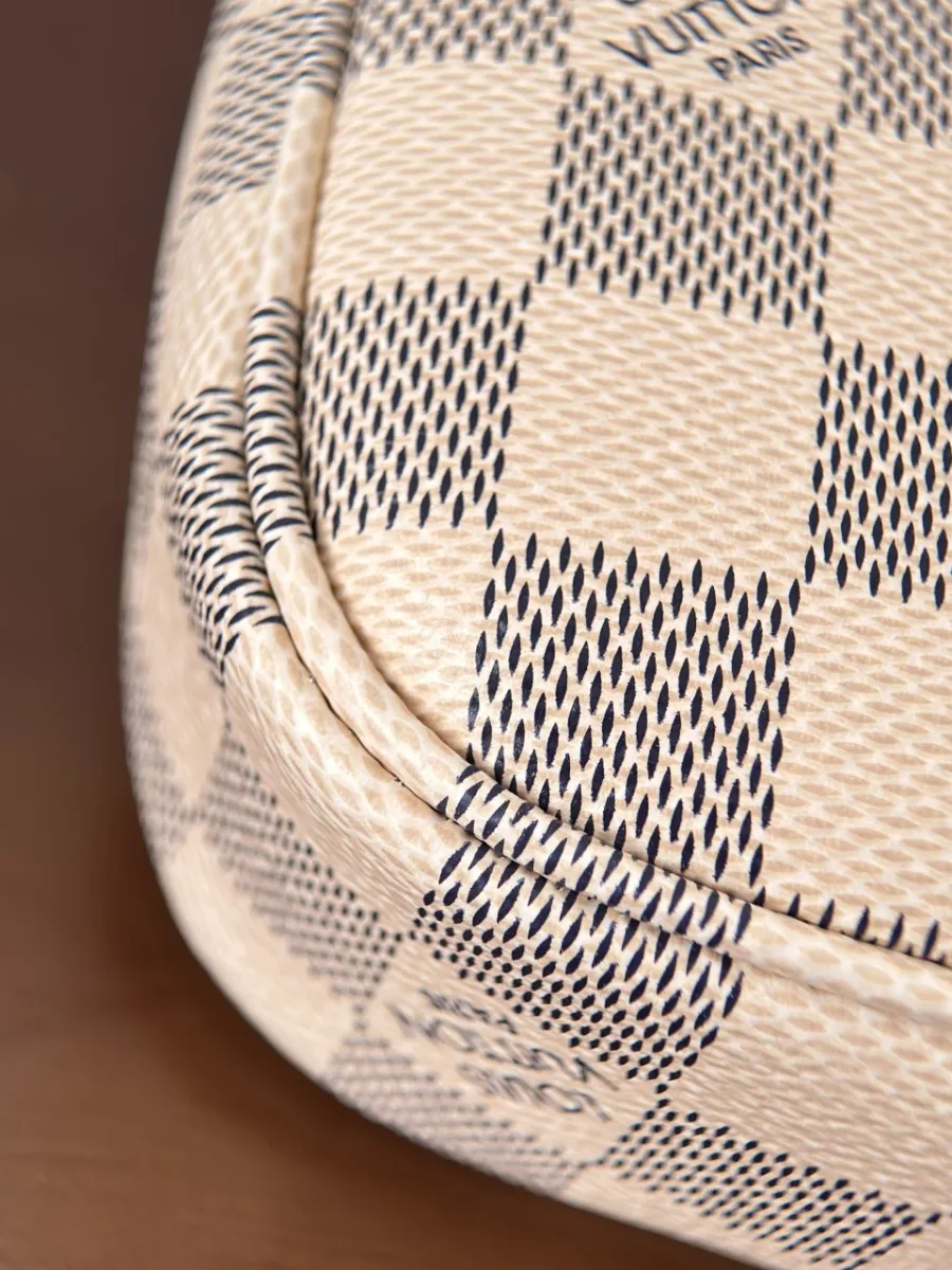 Крупный план угла сумки Louis Vuitton Pochette Accessoires с кожаным кантом