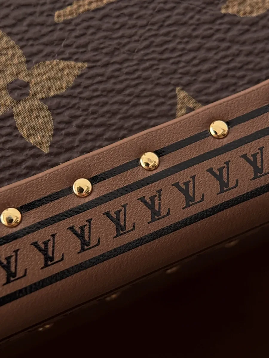 Деталь отделки сумки Louis Vuitton Speedy Trunk с заклепками и монограммами
