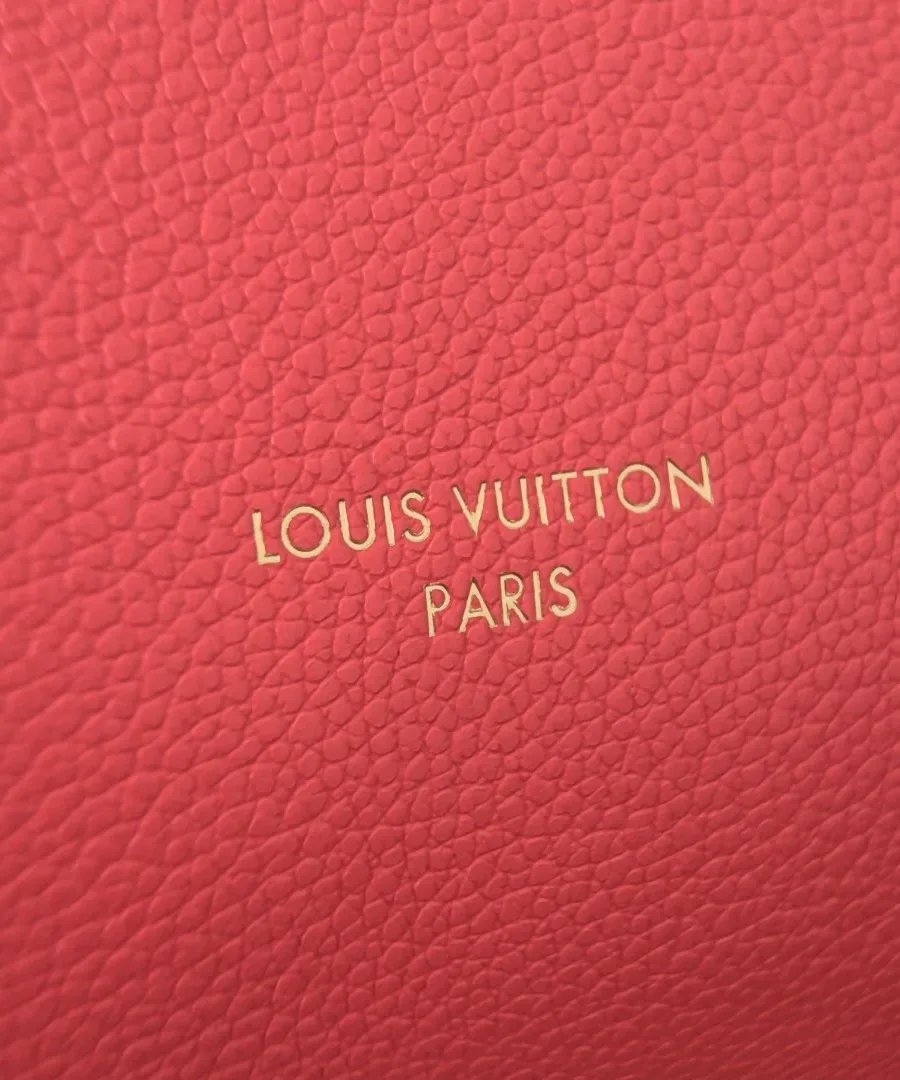 Крупный план золотистого тиснения логотипа Louis Vuitton Paris на розовой коже