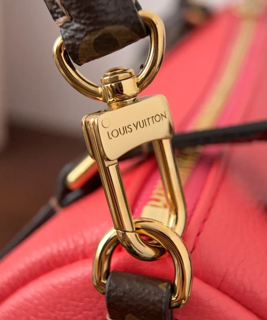 Крупный план золотистого карабина с гравировкой Louis Vuitton