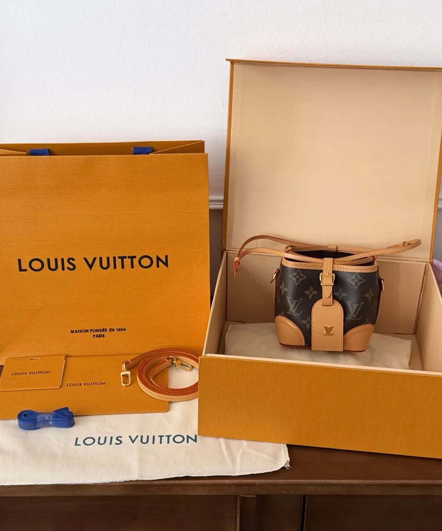 Мини-сумка Louis Vuitton Noé Purse в фирменной коробке рядом с бумажным пакетом