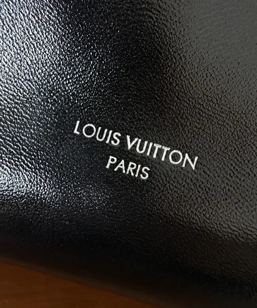 Крупный план серебристого тиснения логотипа Louis Vuitton Paris на черной коже