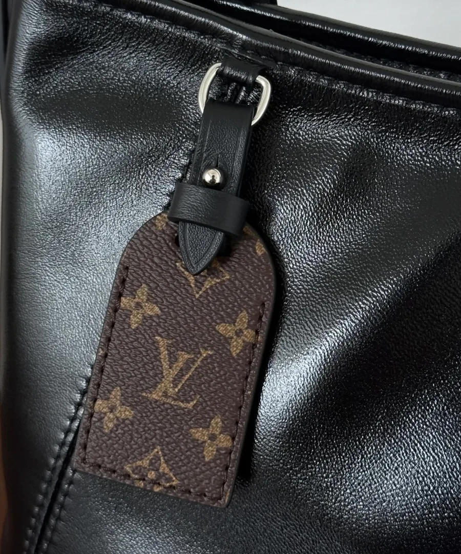 Съемная багажная бирка из канвы Monogram на черной кожаной сумке