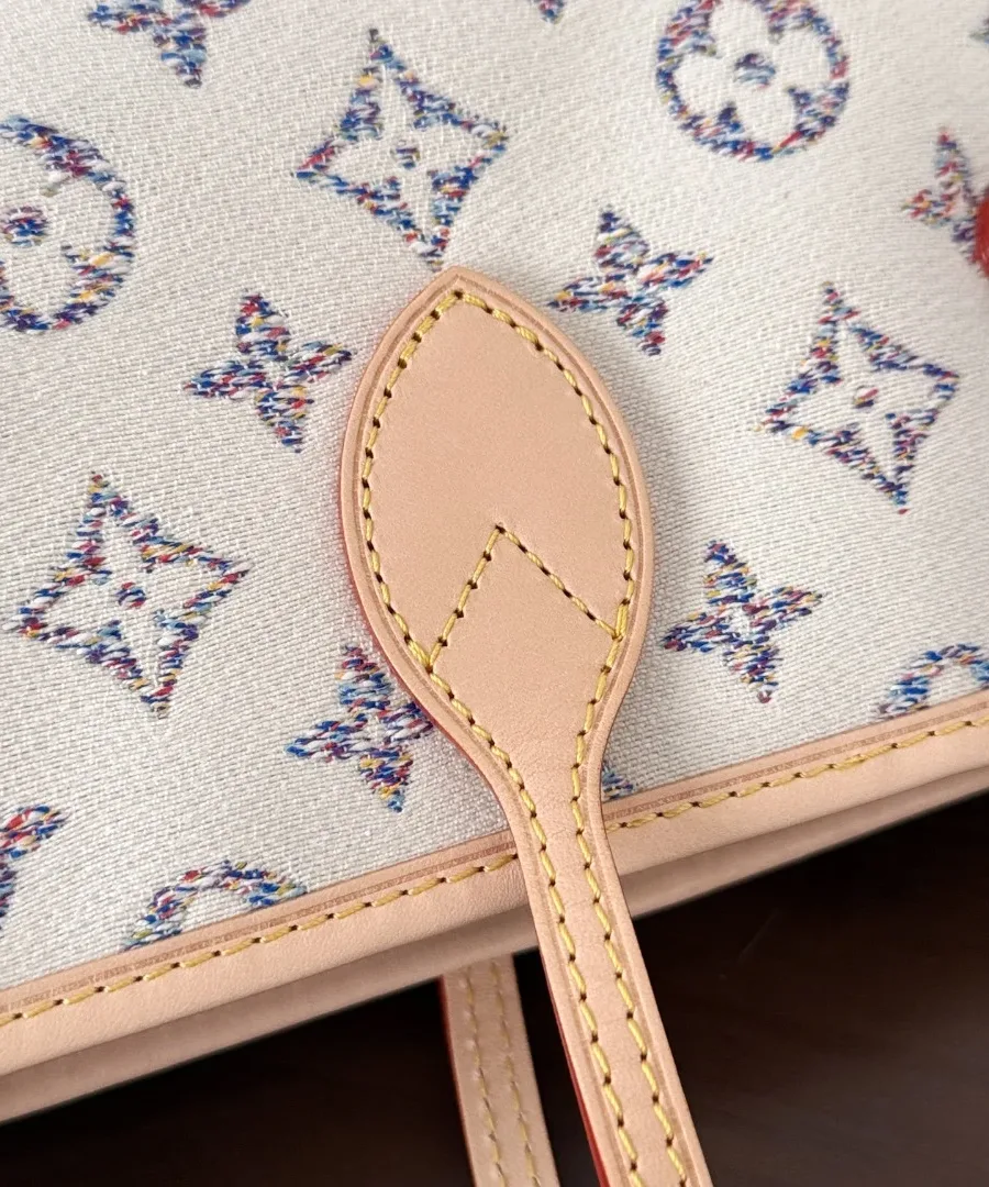 Крупный план фактурного текстиля с разноцветным узором Monogram и креплением кожаной ручки