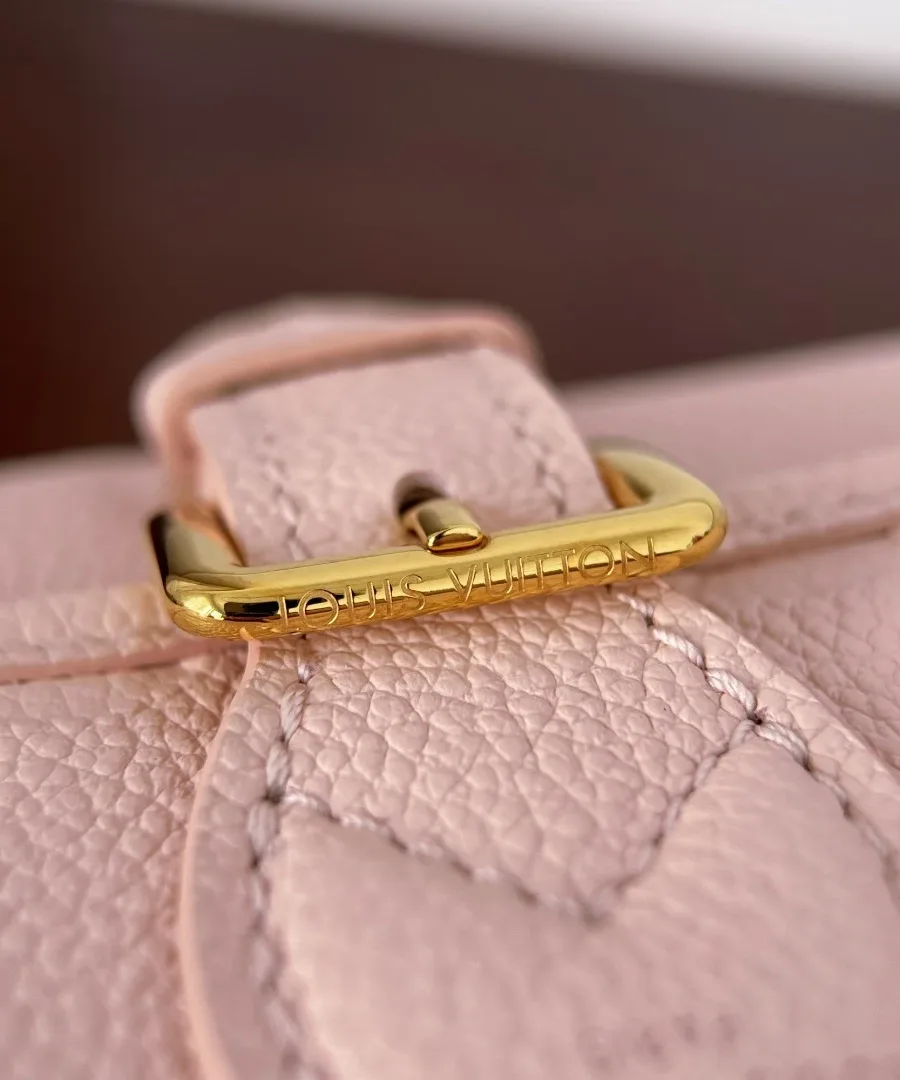 Крупный план золотистой пряжки с гравировкой Louis Vuitton на клапане