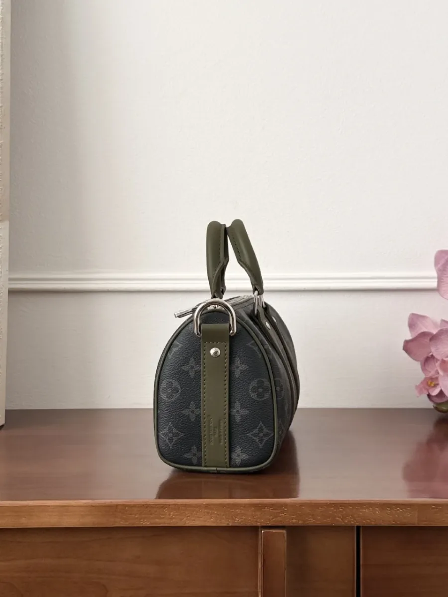 Боковая сторона сумки Keepall 25, демонстрирующая округлую форму и зелёную кожаную полосу
