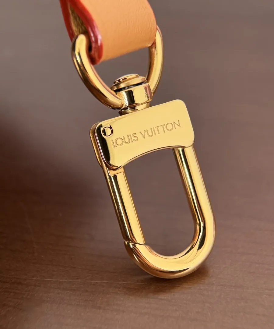 Крупный план золотистого карабина с гравировкой Louis Vuitton