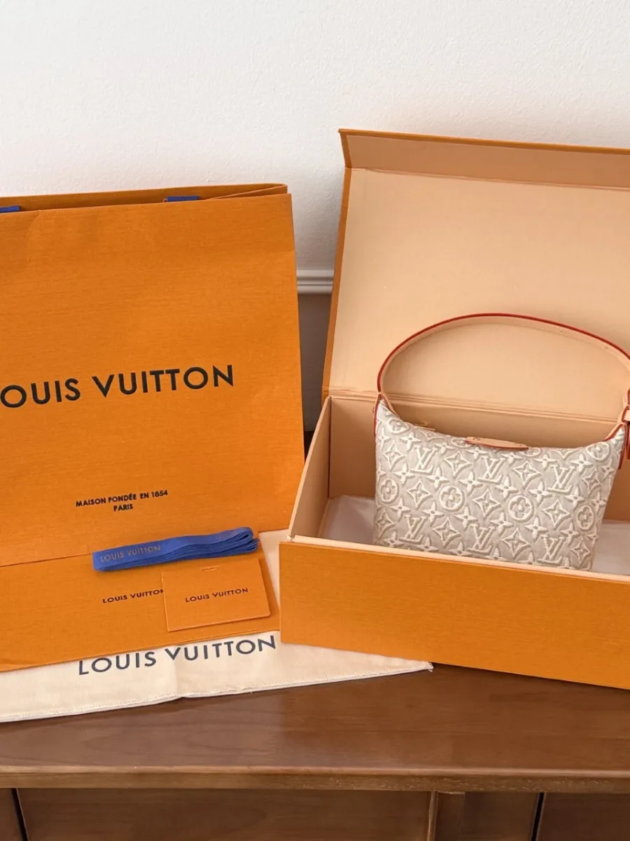 Сумка рядом с фирменной оранжевой коробкой и пакетом Louis Vuitton