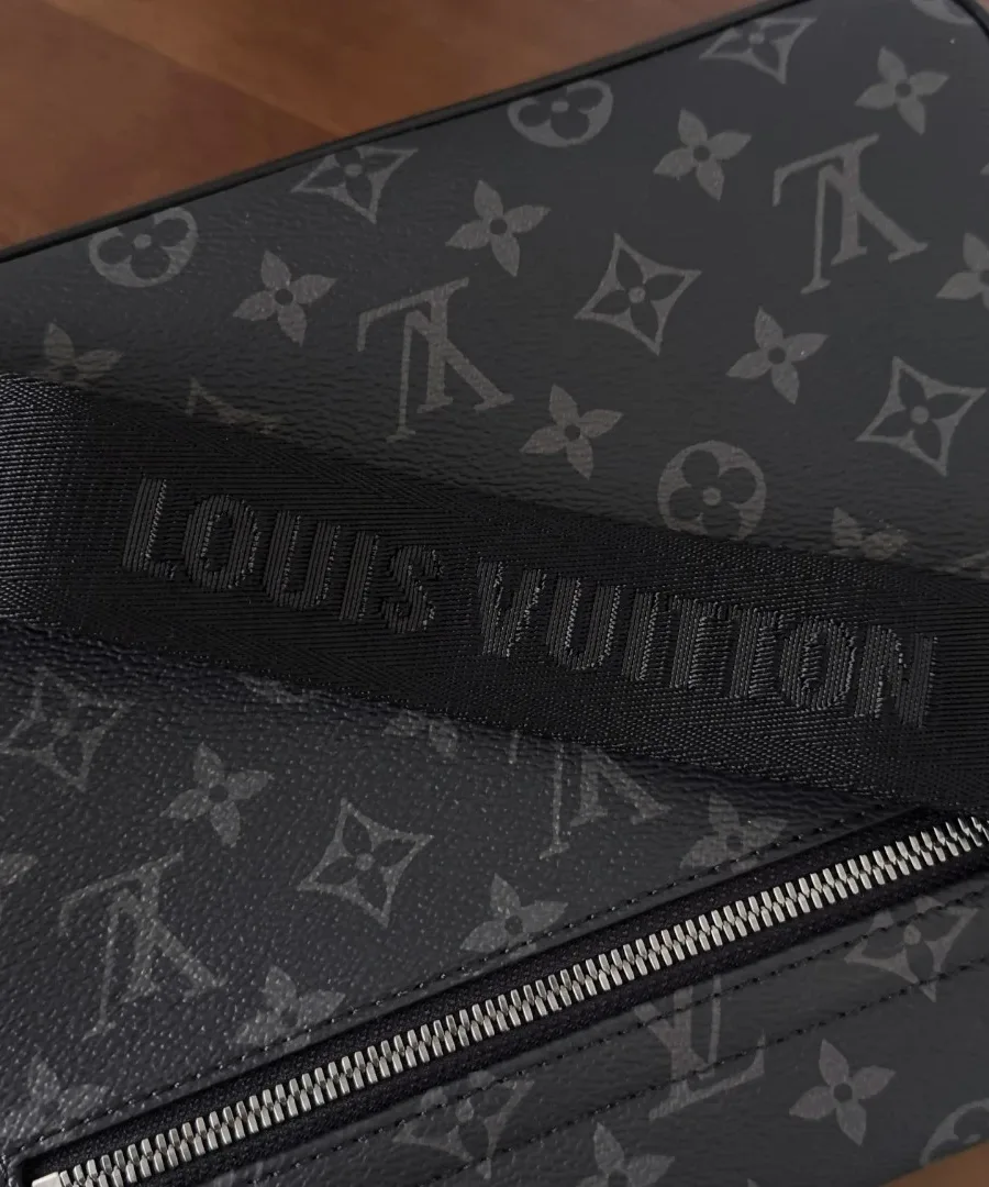 Вид на заднюю часть сумки и текстильный ремень с надписью Louis Vuitton