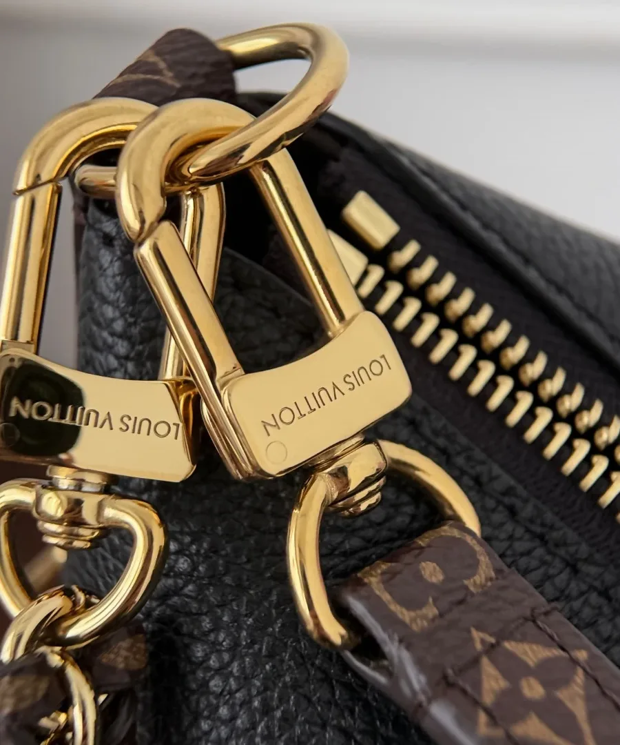 Крупный план золотистых карабинов с гравировкой Louis Vuitton