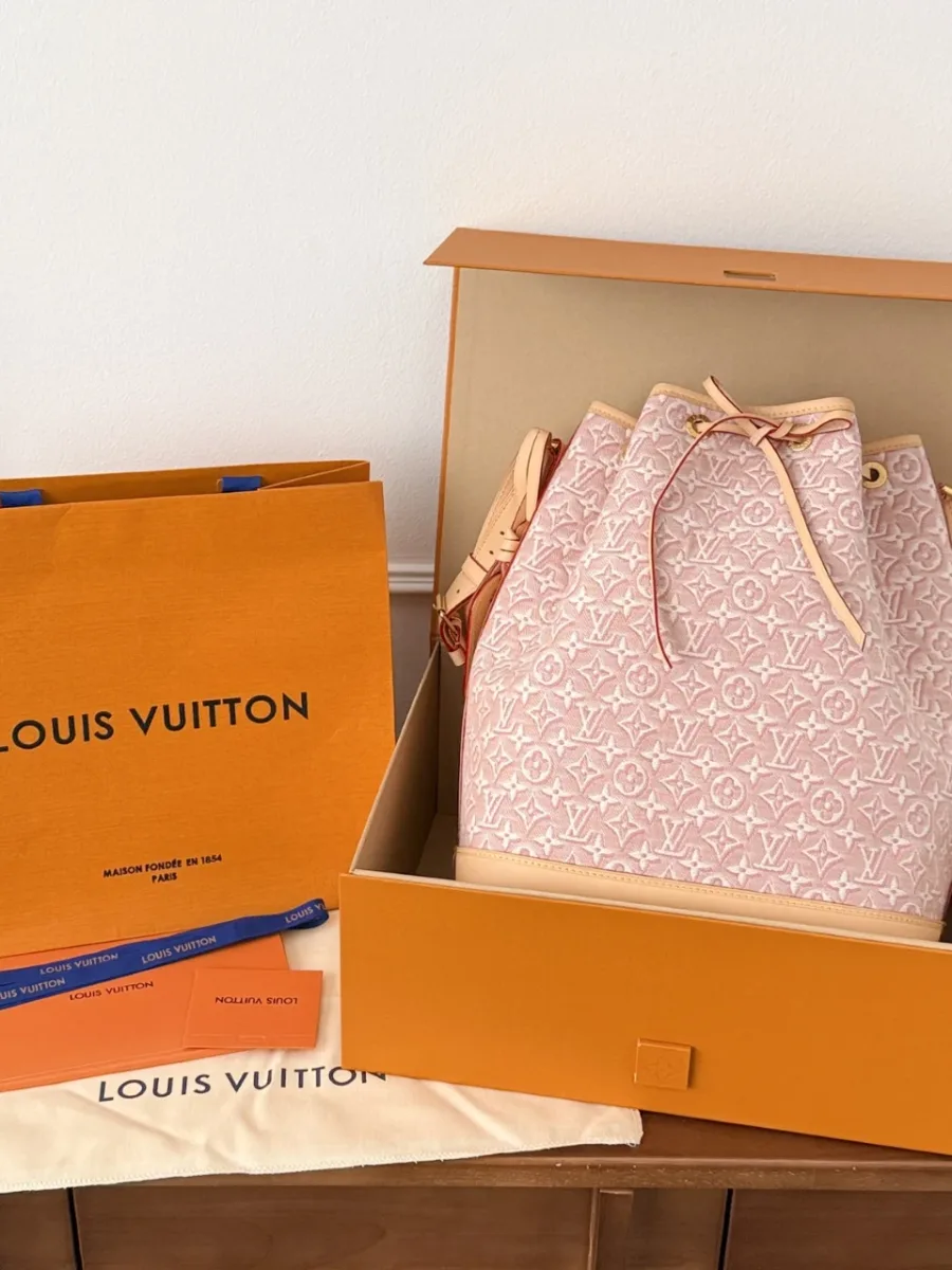 Розовая сумка Louis Vuitton Noé рядом с фирменной коробкой и пакетом