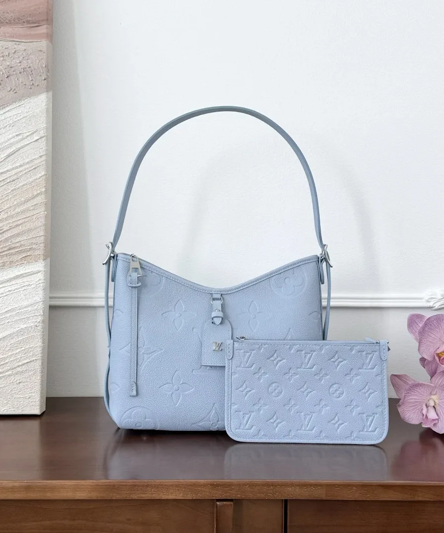 Голубая сумка Louis Vuitton Carryall PM со съемным клатчем на деревянном столе