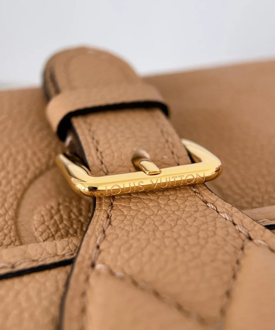 Крупный план золотистой пряжки на клапане сумки Louis Vuitton