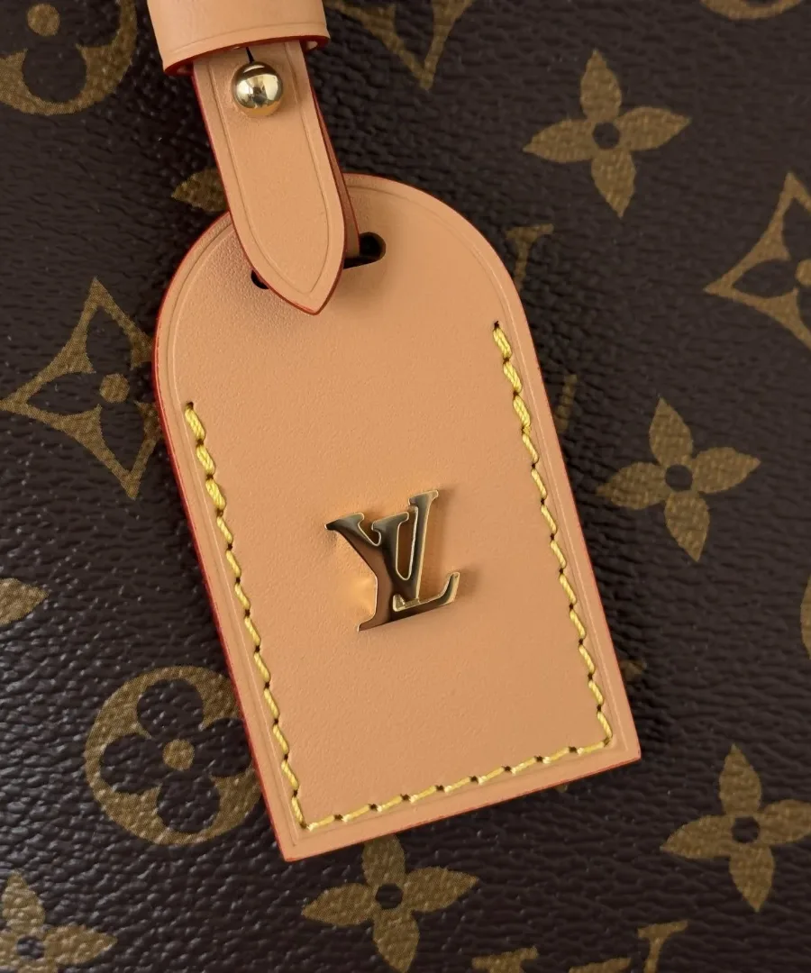 Крупный план кожаного ярлыка с золотистым логотипом LV на сумке Louis Vuitton