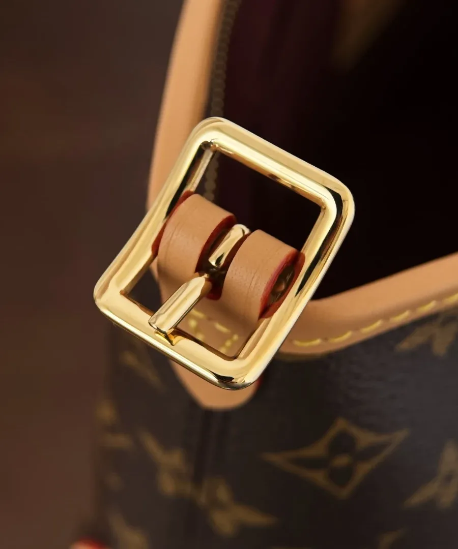Крупный план золотистой пряжки на плечевом ремне сумки Louis Vuitton
