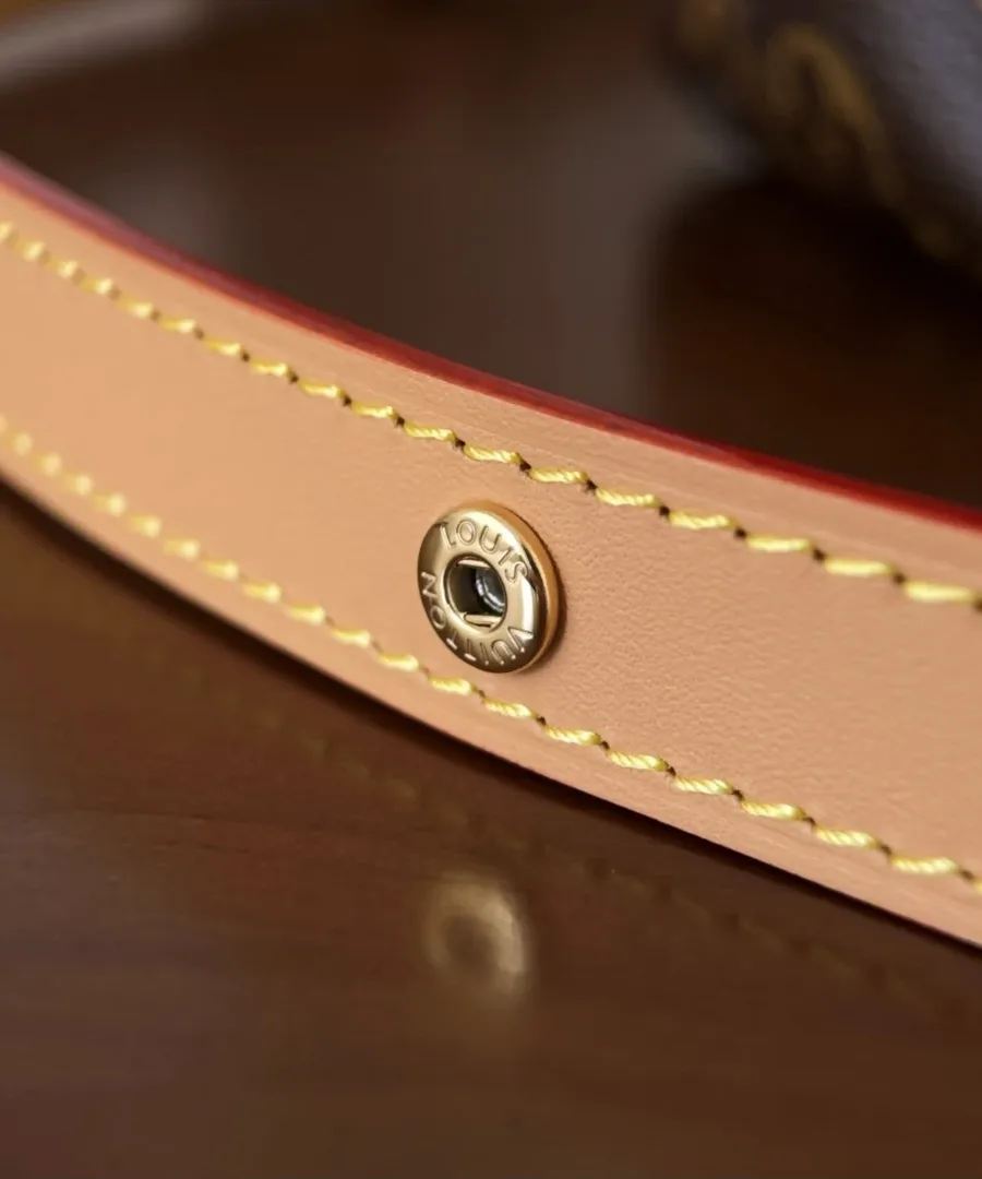 Деталь кожаного ремня сумки Louis Vuitton с золотистой кнопкой