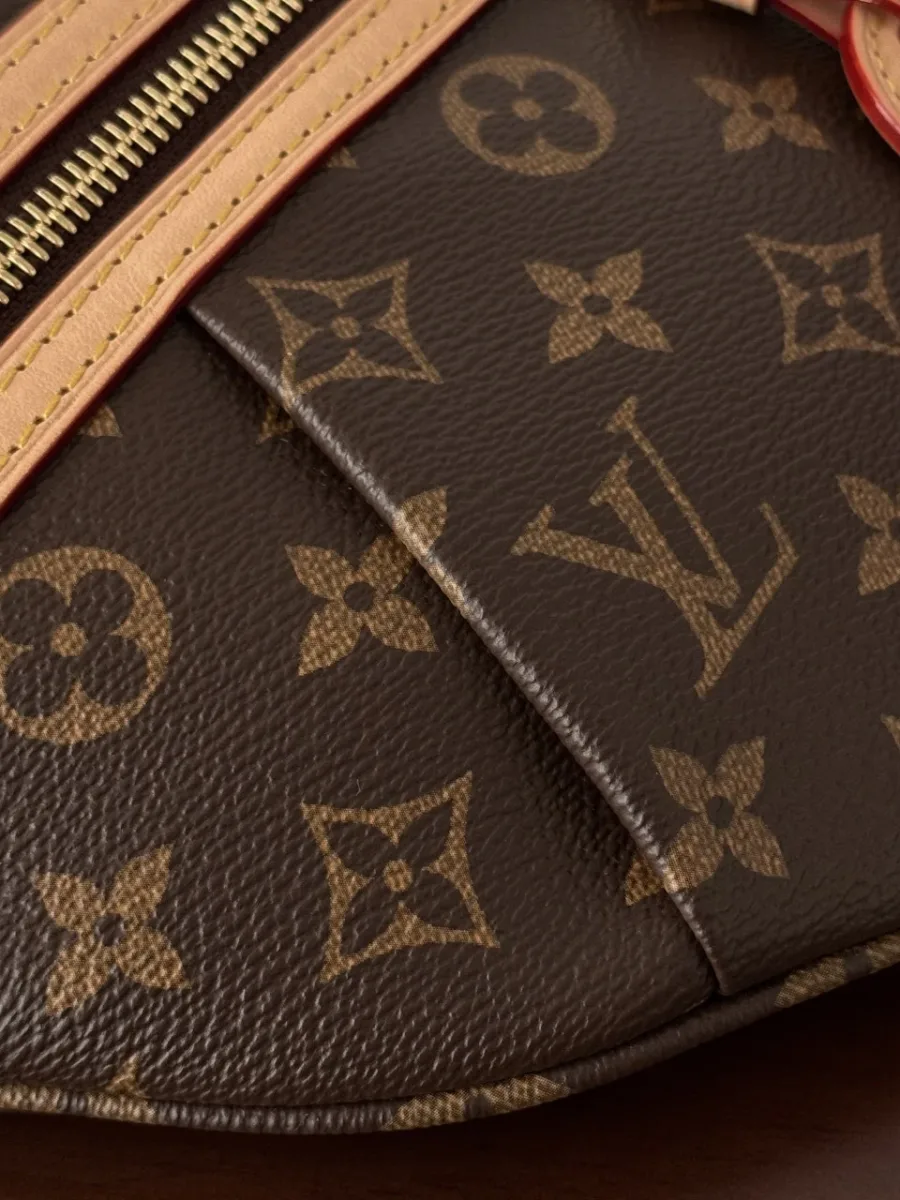 Деталь аккуратных швов и стыка канвы Monogram на корпусе поясной сумки.