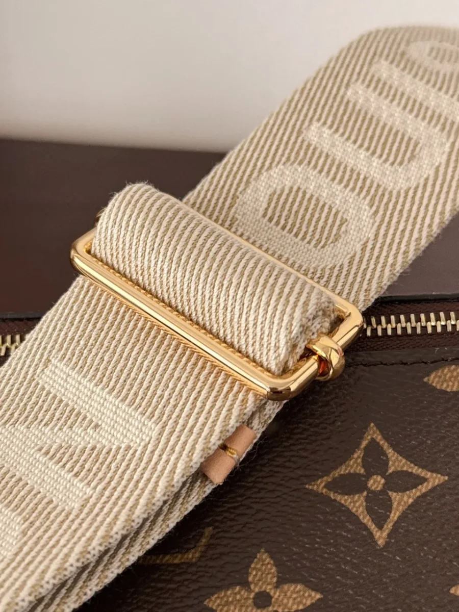 Крупный план регулируемого текстильного ремня с надписью Louis Vuitton.
