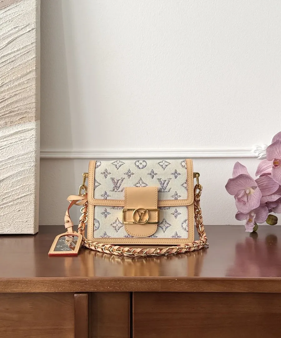 Разноцветная сумка Louis Vuitton Dauphine Mini с золотистой цепочкой на деревянном столе.