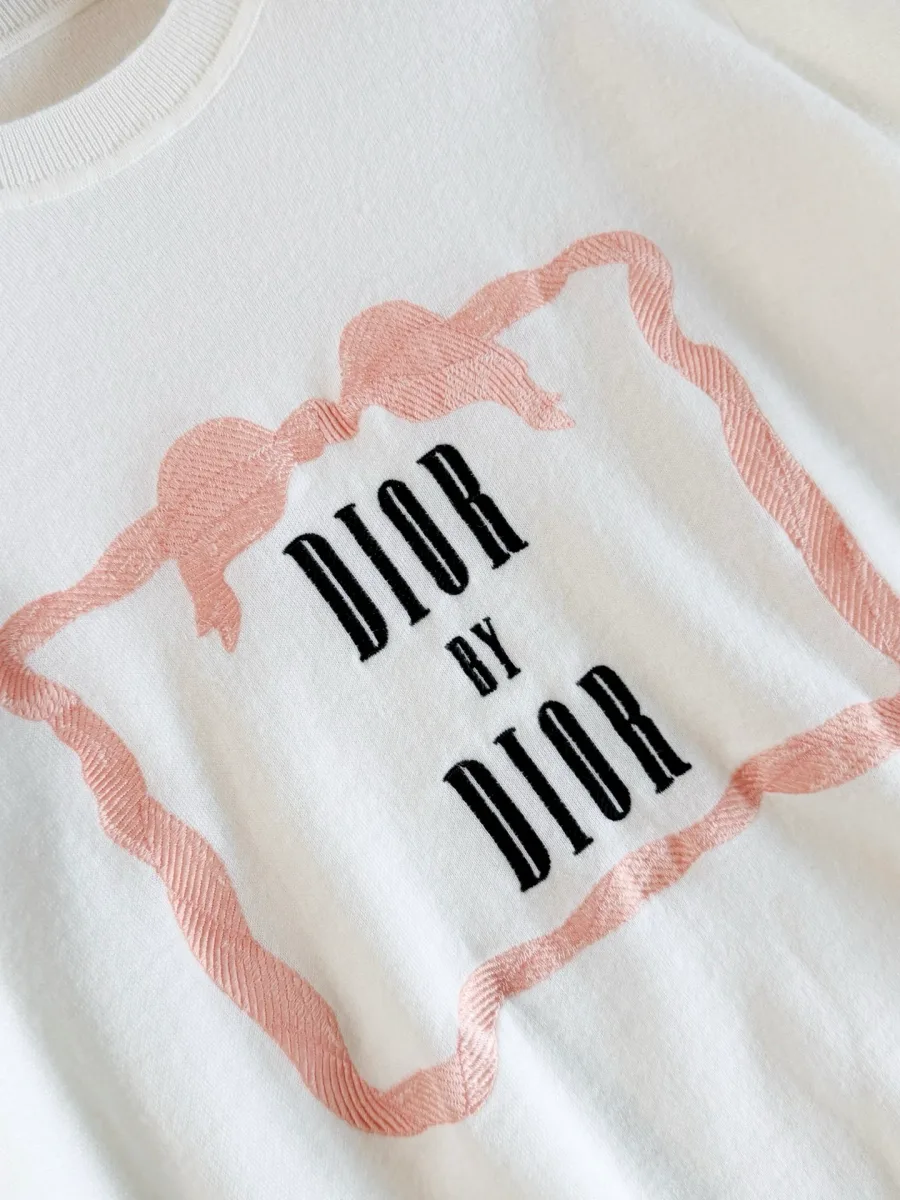 Крупный план надписи Dior by Dior в обрамлении розовой рамки с бантом