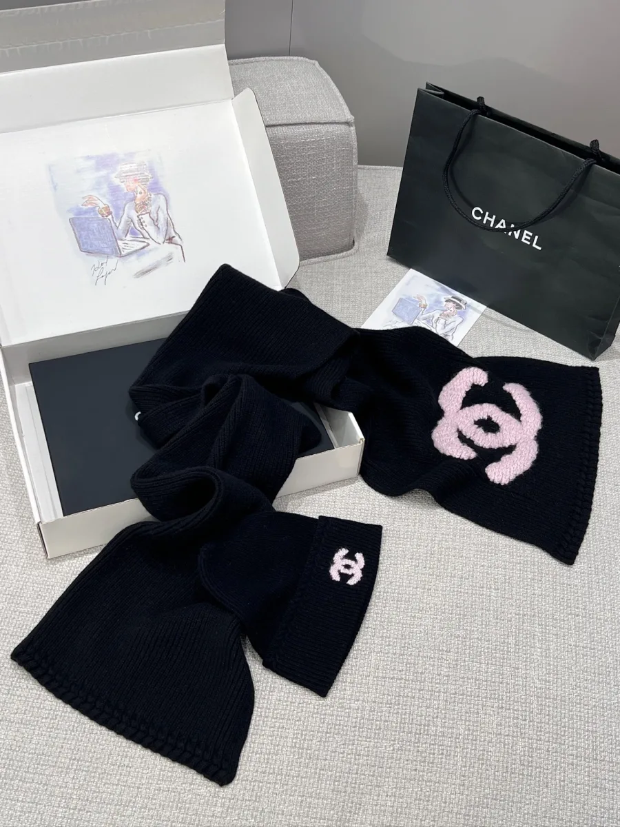 Разложенный чёрный вязаный шарф и шапка на фоне подарочной упаковки Chanel