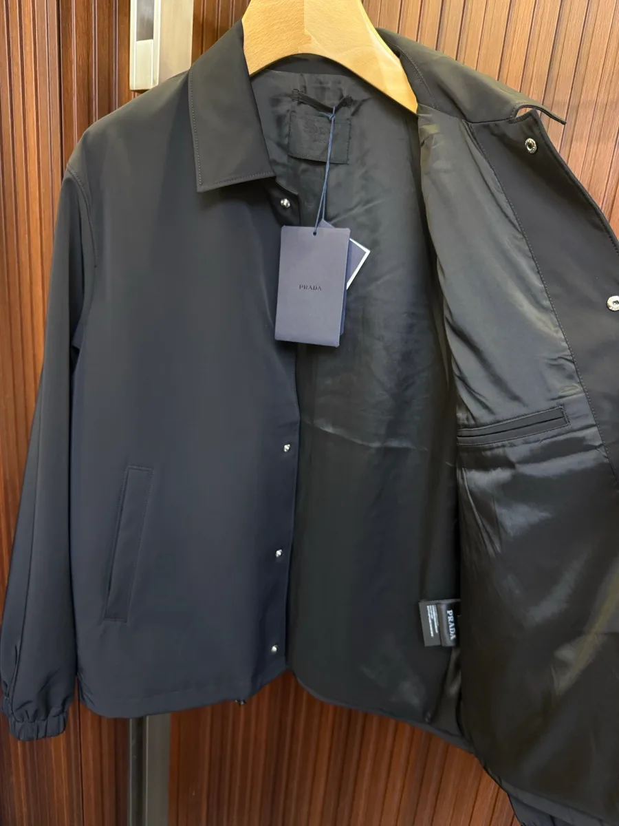 Чёрная куртка в расстёгнутом виде: внутренняя гладкая подкладка, бирка и потайной карман