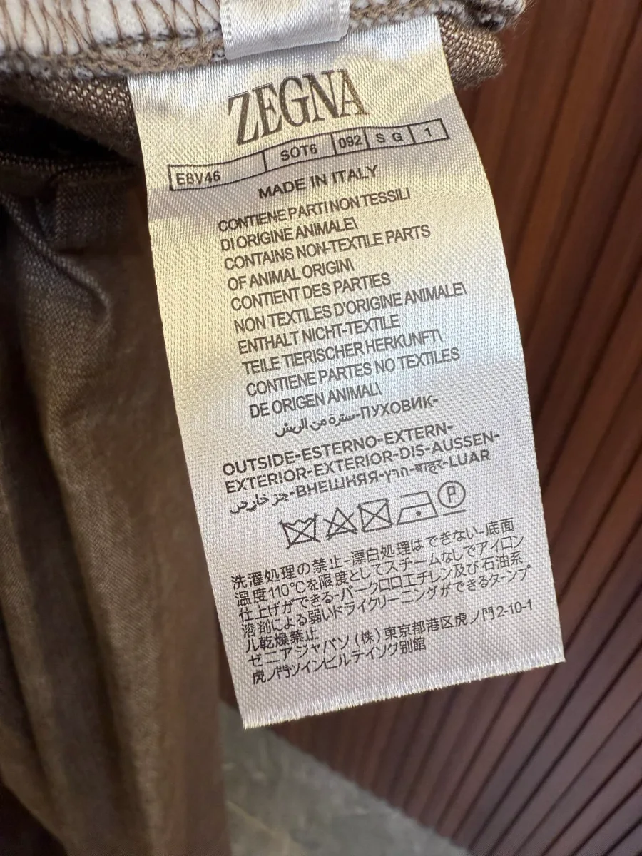 Внутренний тканевый ярлык брюк Zegna с указанием бренда и информации об уходе