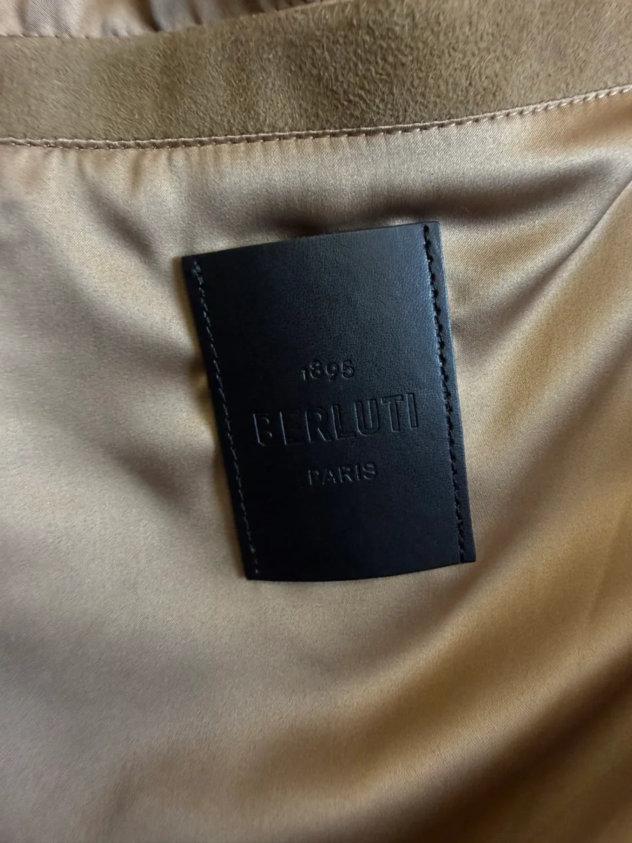 Кожаная нашивка Berluti Paris на подкладке у горловины бежевой куртки