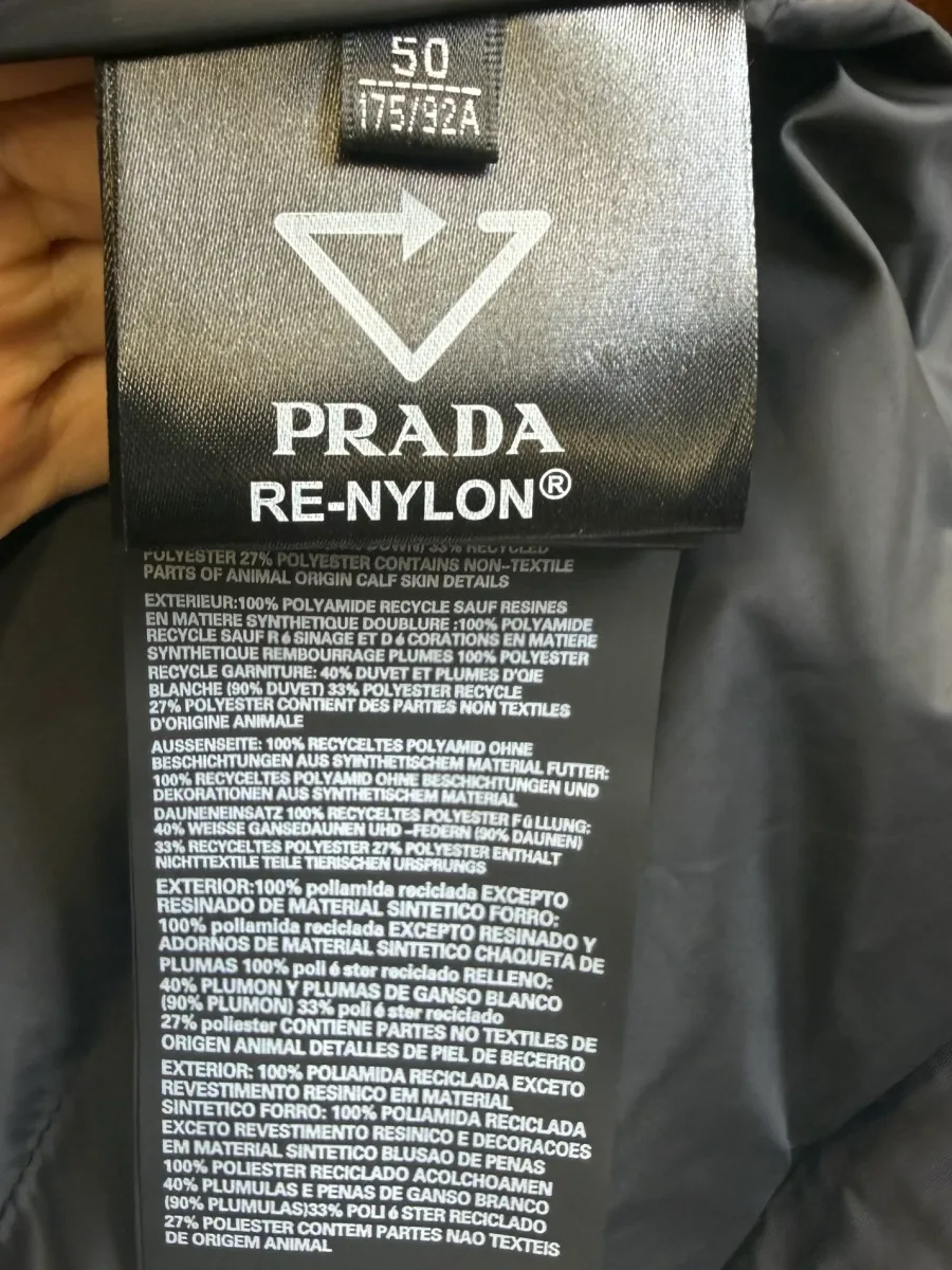 Вшитый ярлык изделия Prada Re-Nylon с указанием размера 50 и состава материалов с гусиным пухом