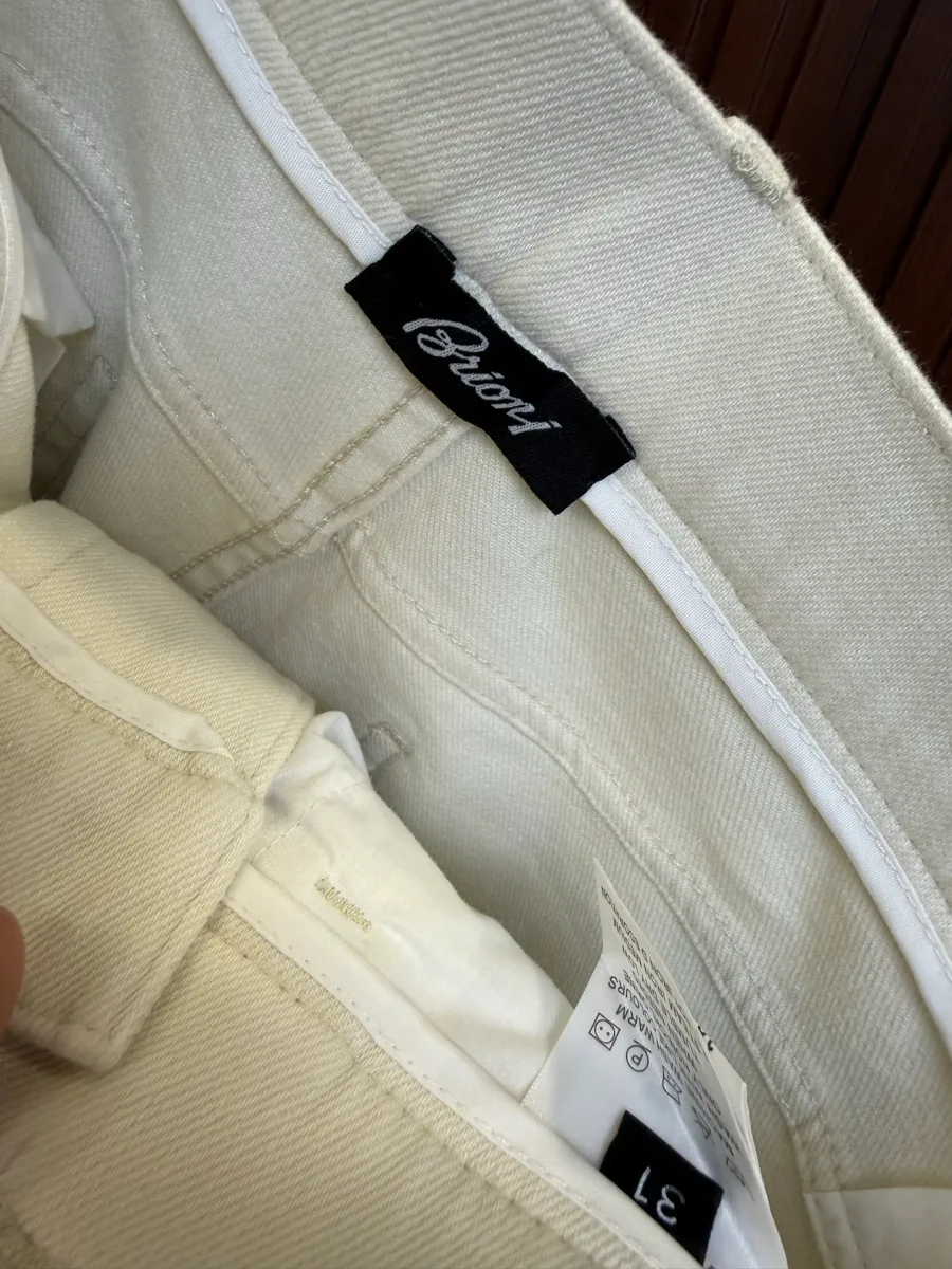 Внутренняя сторона пояса белых брюк с логотипом Brioni и металлической молнией