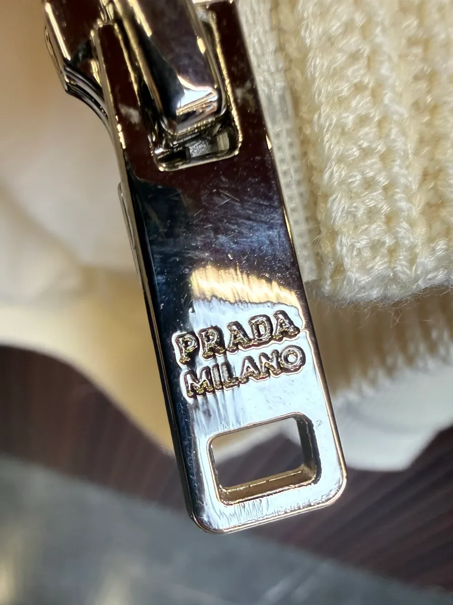 Металлический серебристый пуллер молнии с выгравированным логотипом Prada Milano крупным планом
