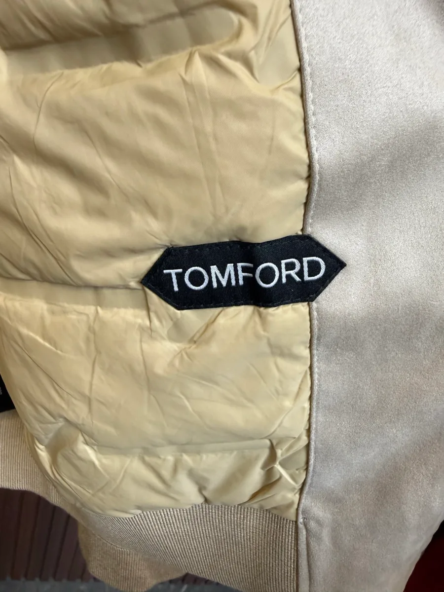 Крупный план стеганой подкладки пуховика с контрастной фирменной нашивкой Tom Ford