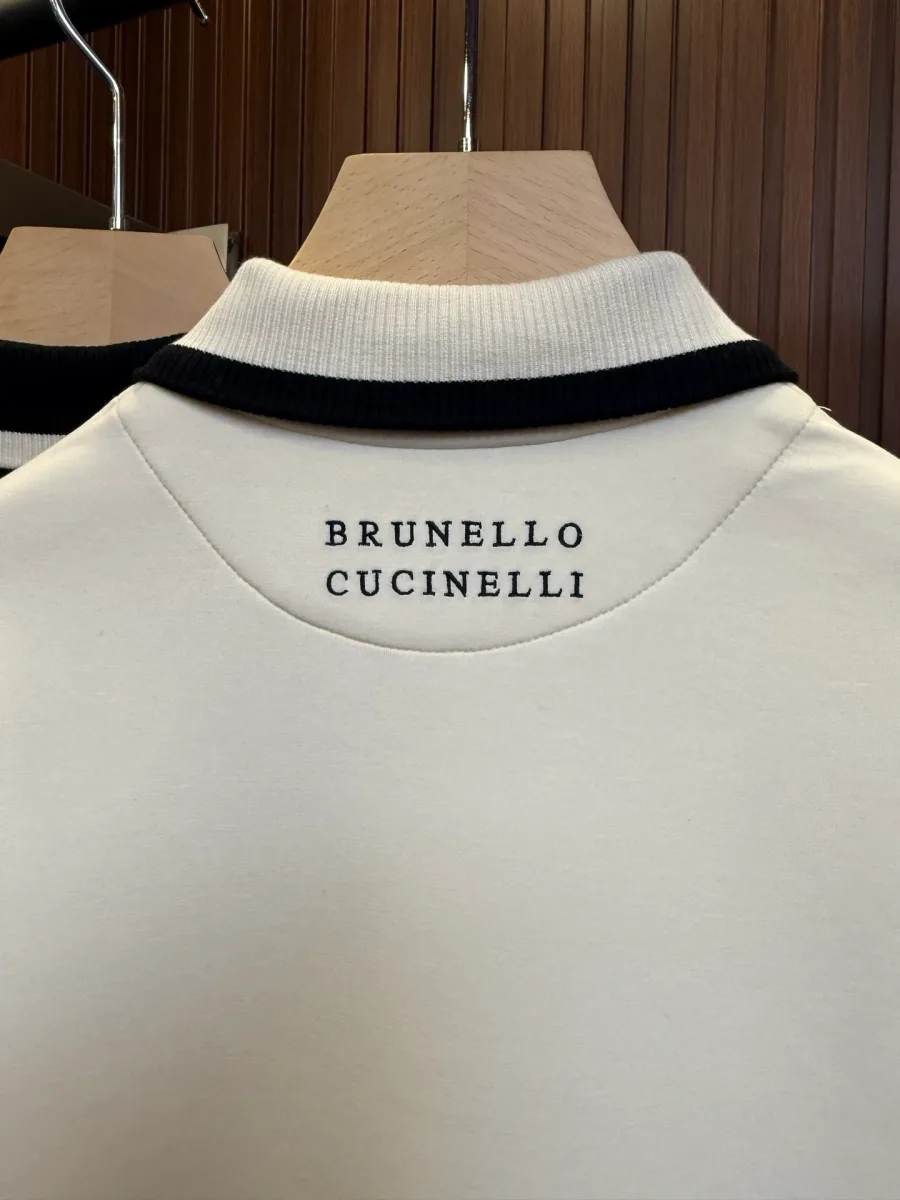 Крупный план спинки бежевого поло: вышитая надпись Brunello Cucinelli под воротником с тёмным кантом