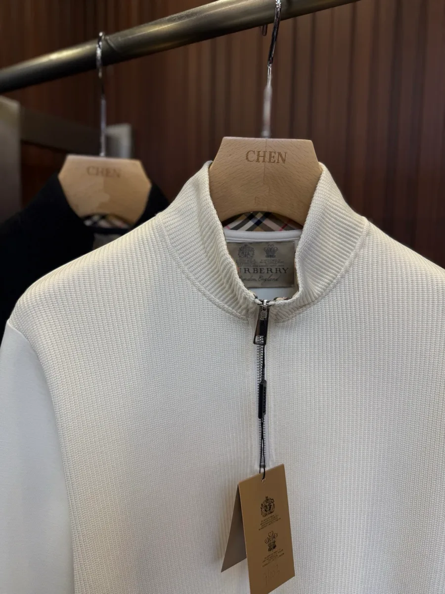 Крупный план воротника-стойки с короткой молнией и фирменной биркой Burberry.