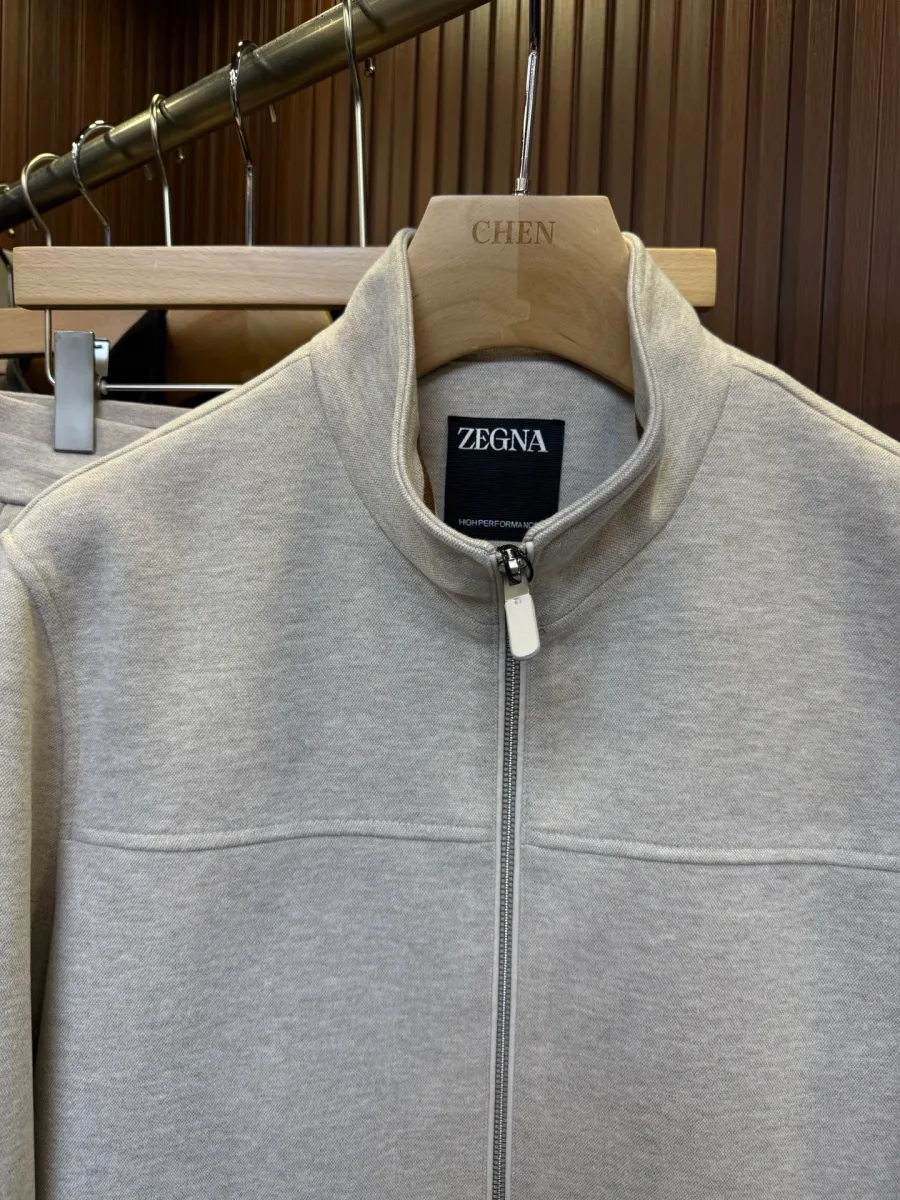Воротник-стойка бежевой куртки Zegna с металлической молнией и биркой бренда