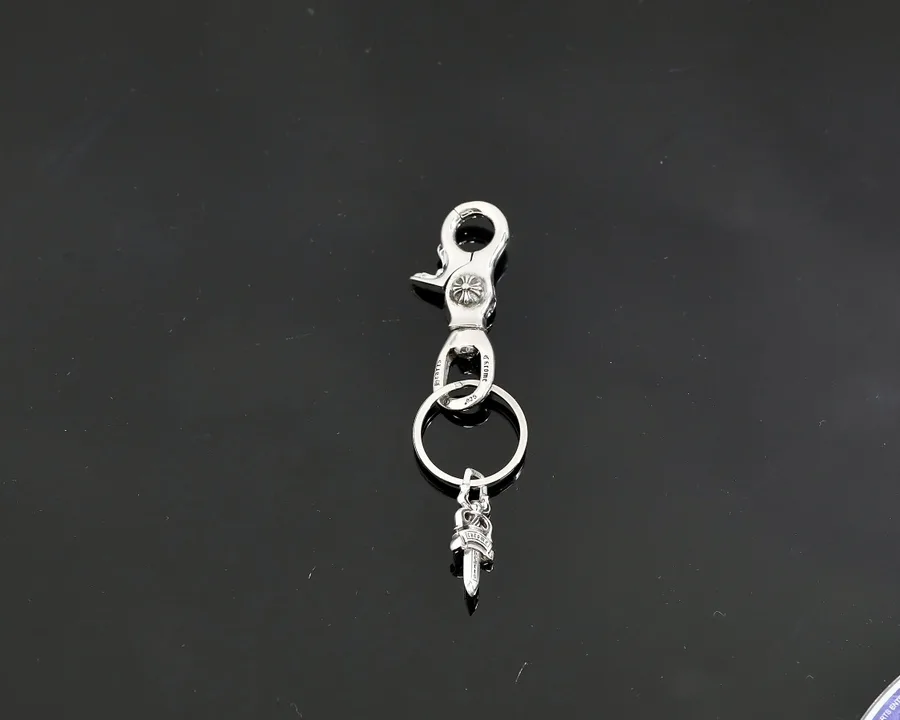 Серебряный брелок Chrome Hearts с карабином и подвеской Dagger на темном фоне