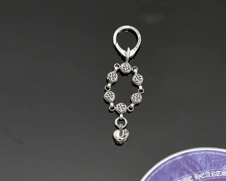 Серебряный кулон для сумки Chrome Hearts с резными бусинами и подвеской в виде сердца на темном фоне