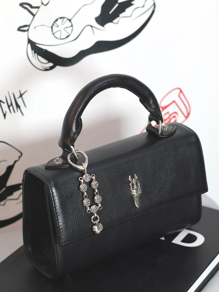 Серебряный кулон Chrome Hearts, закрепленный на ручке черной кожаной сумки