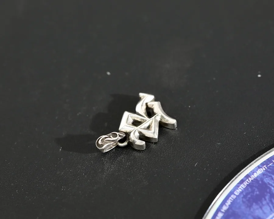 Вид сбоку на рельефную серебряную подвеску Chrome Hearts R