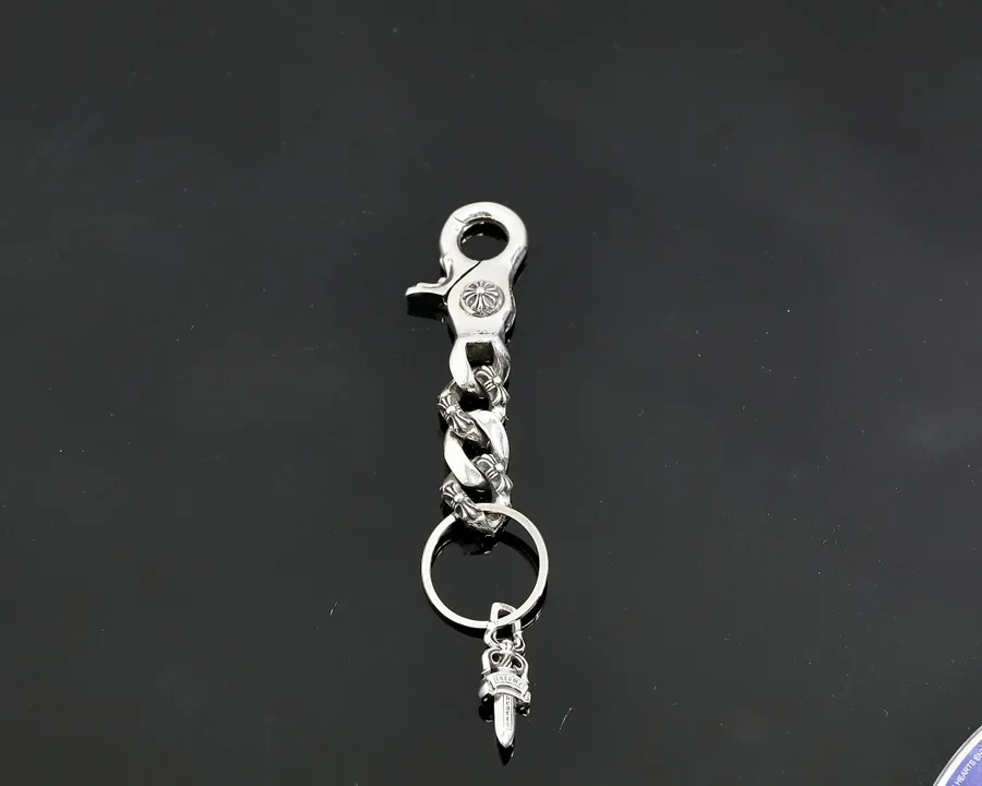 Серебряный брелок Chrome Hearts с карабином, цепочкой и подвеской в виде кинжала Dagger на темном фоне