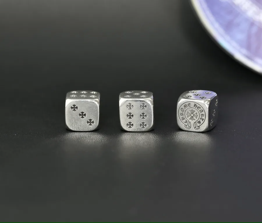 Серебряные игральные кубики Chrome Hearts в ряд на темном фоне